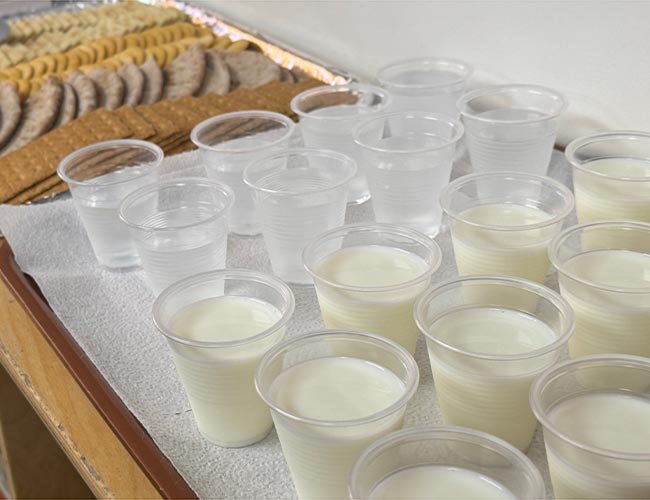 cups filled with fresh milk and water arranged for child snack time.
